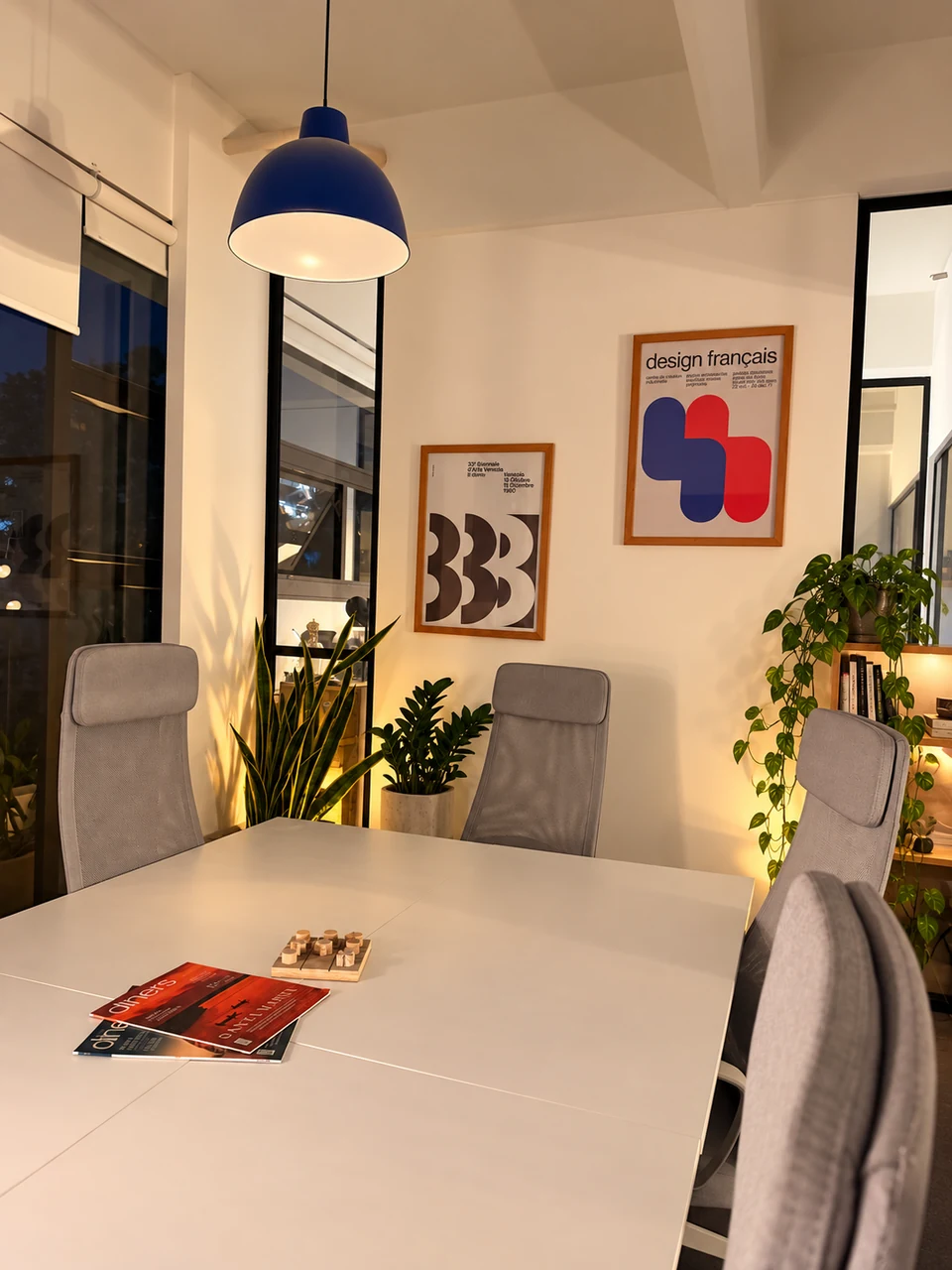 Meeting table with books and magazines, framed artwork and plants
